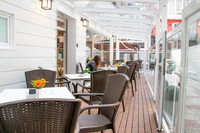 Una mujer está sentada en una mesa en un restaurante con mesas y sillas.