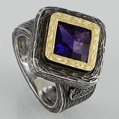 Um anel quadrado de ametista em uma estrutura de prata texturizada com uma borda decorativa em ouro.