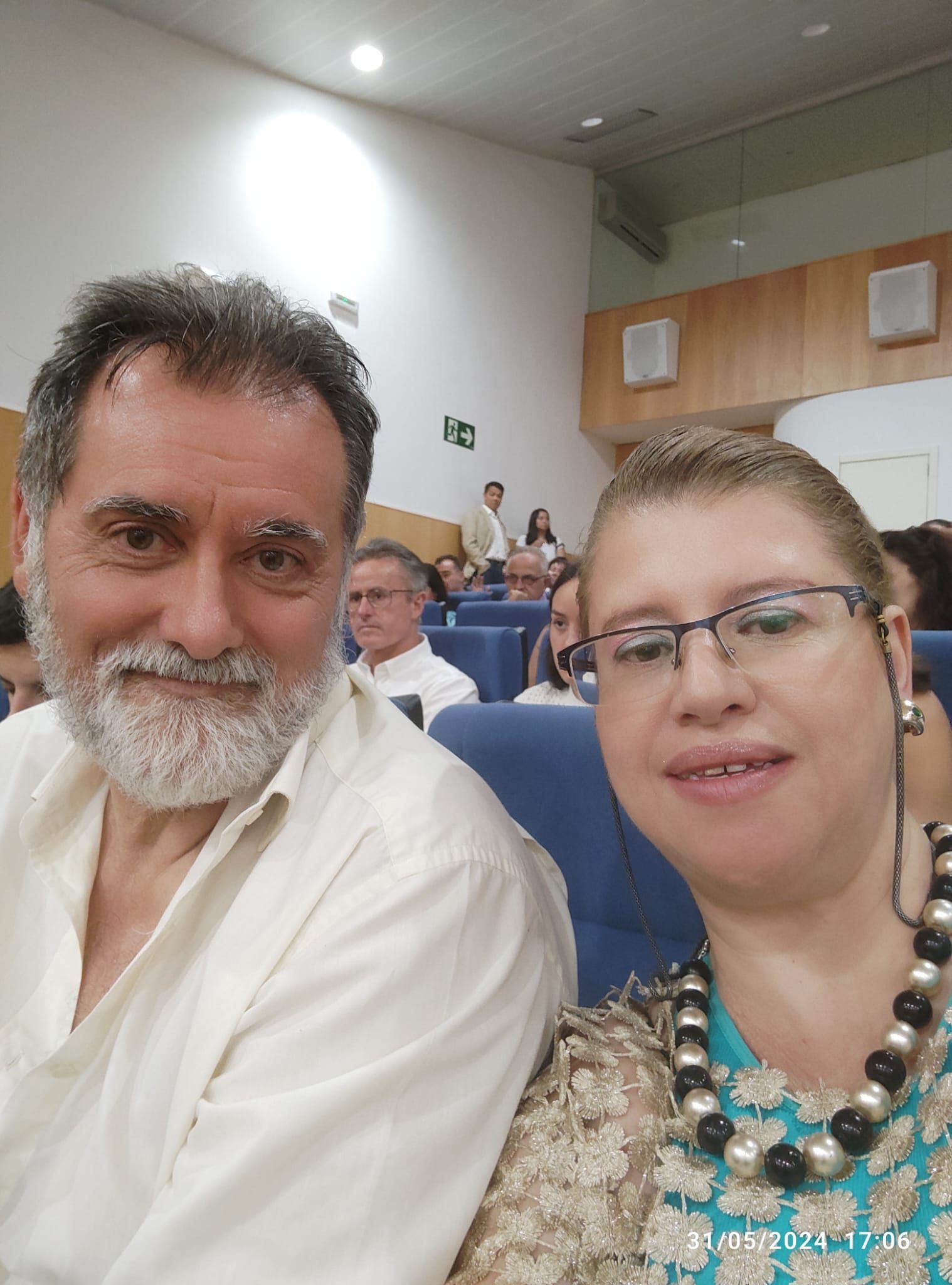 Un hombre y una mujer posan para una fotografía en un auditorio.