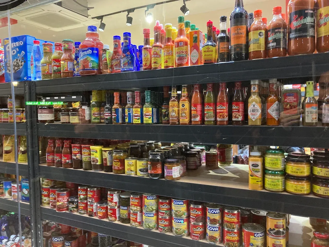 Estantes repletos de diversas salsas picantes y productos enlatados en una tienda.