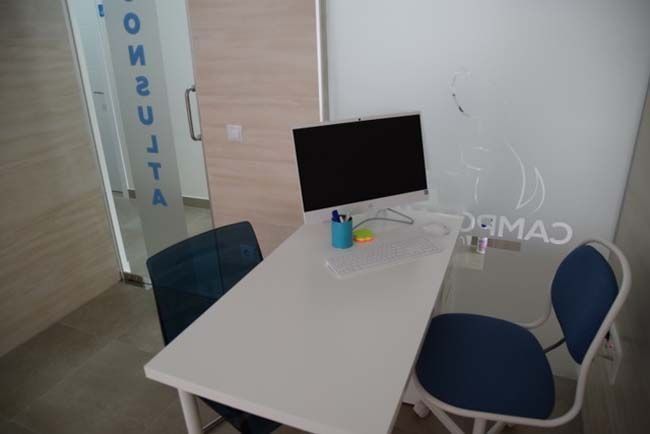 Una mesa blanca con una computadora encima y una silla.