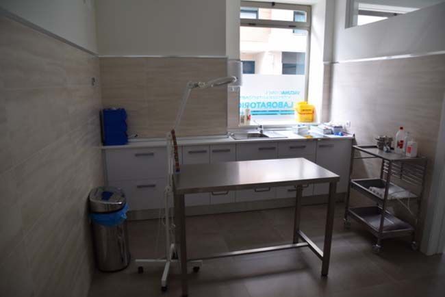 Una habitación con una mesa de acero inoxidable y un bote de basura.