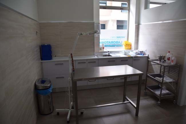 Una habitación con una mesa de acero inoxidable y un bote de basura.