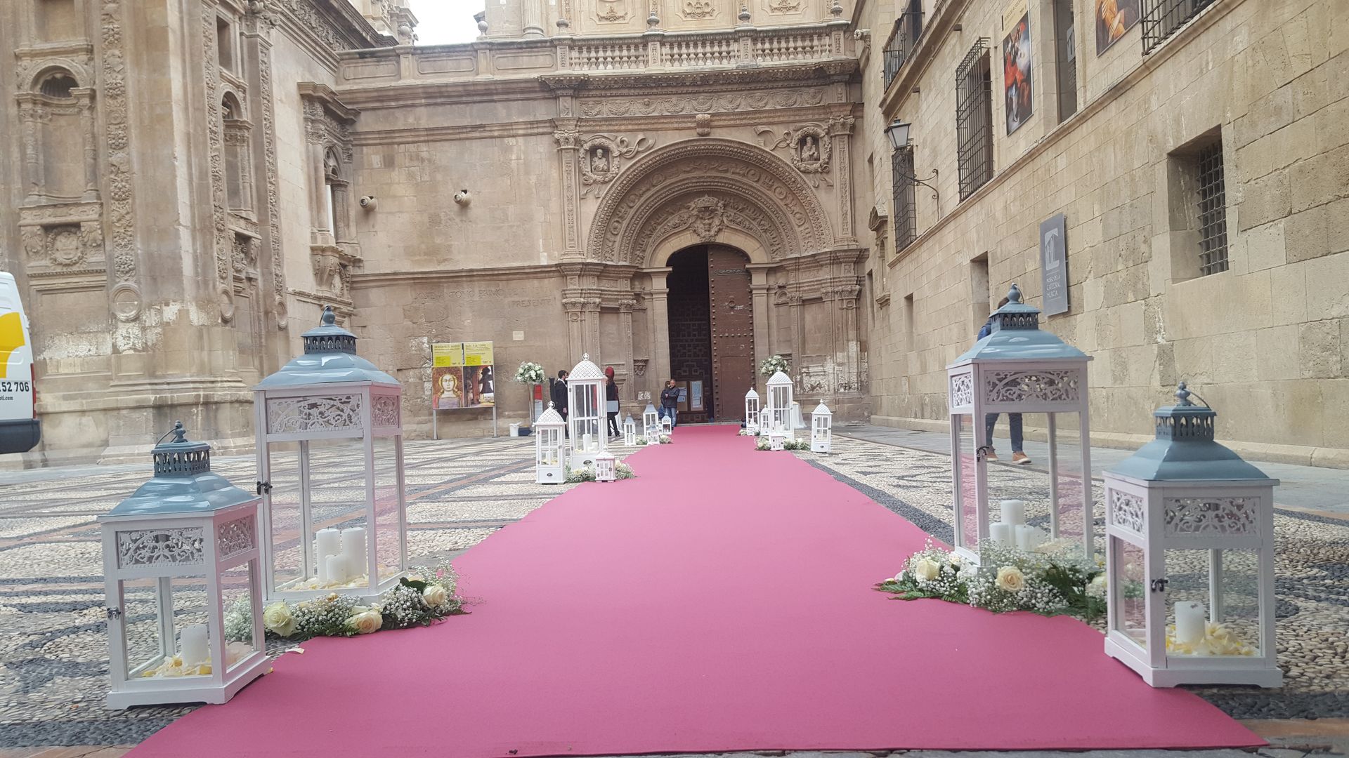 Una alfombra roja está cubierta de linternas y flores frente a un edificio.