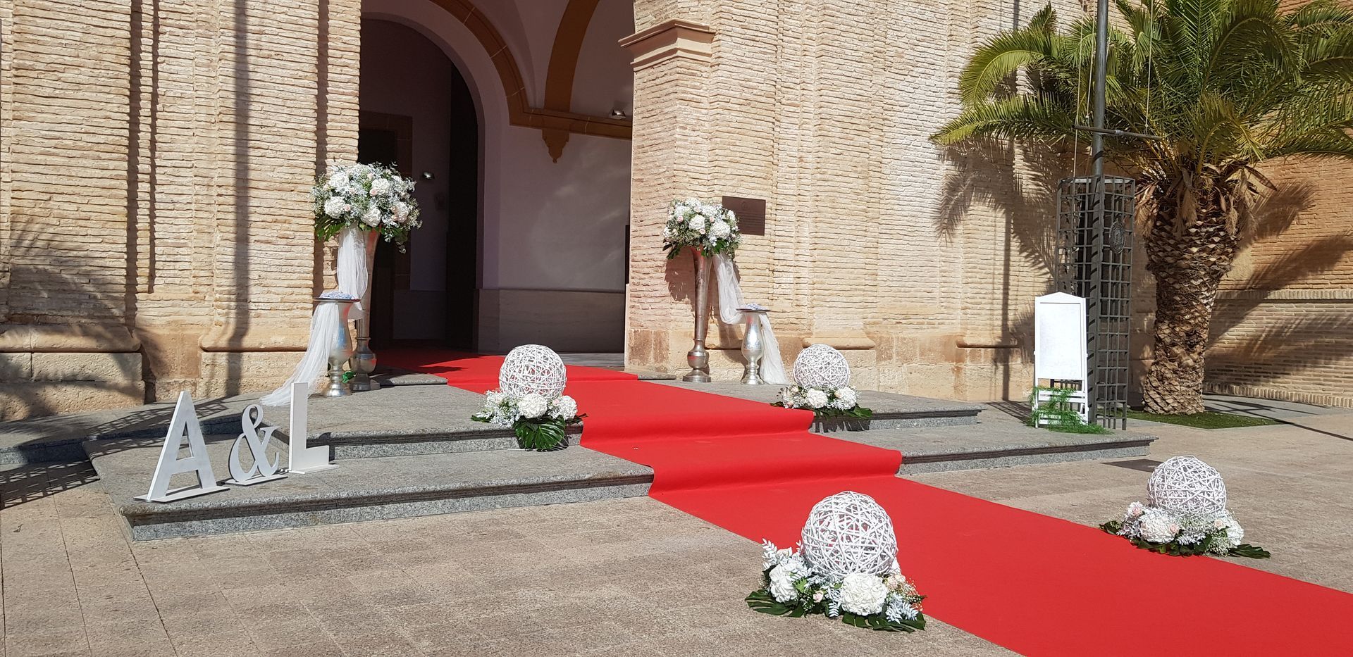 Una alfombra roja conduce a una iglesia decorada con flores blancas.