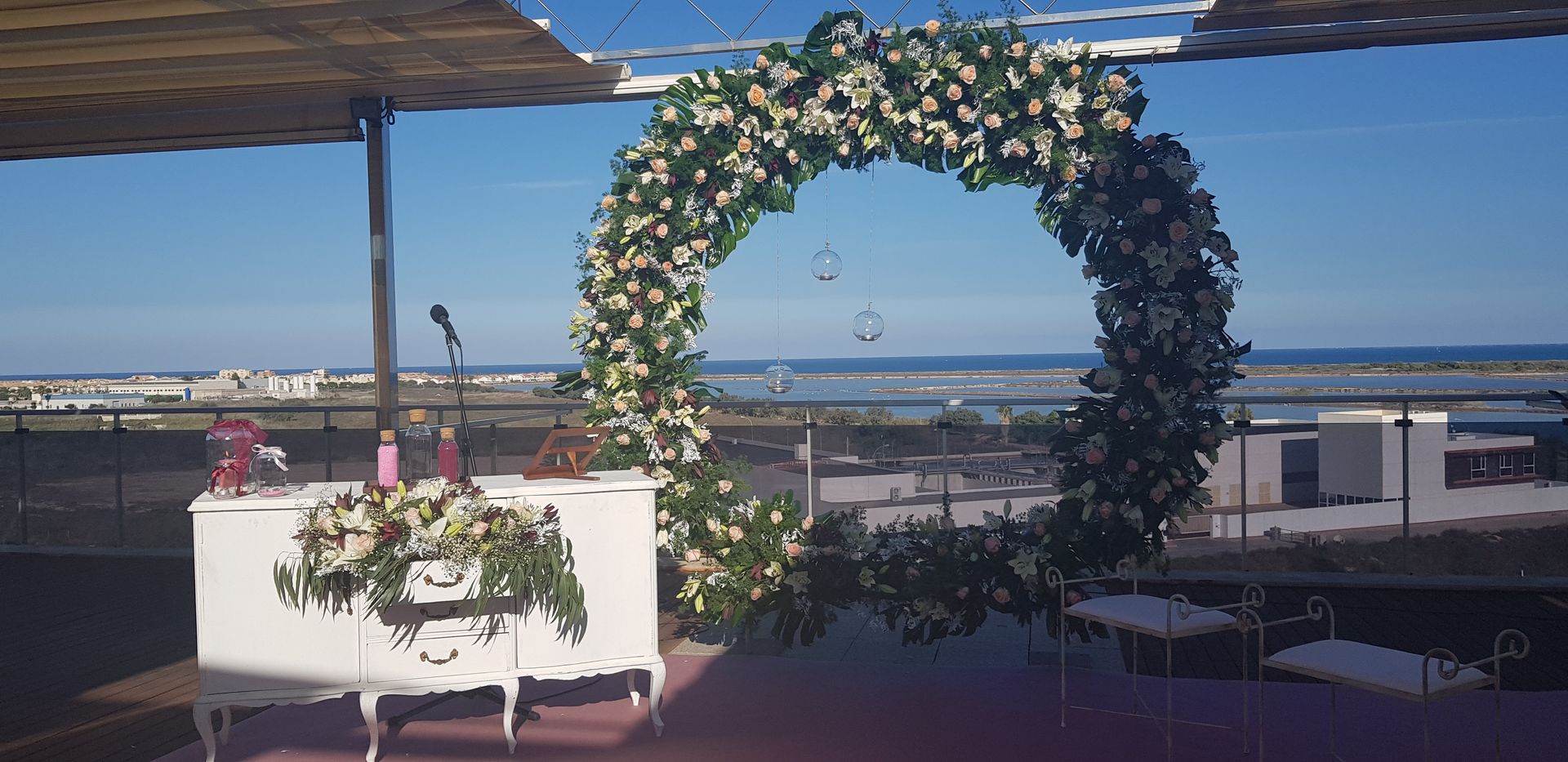 Se está celebrando una ceremonia de boda en un balcón con vistas al océano.