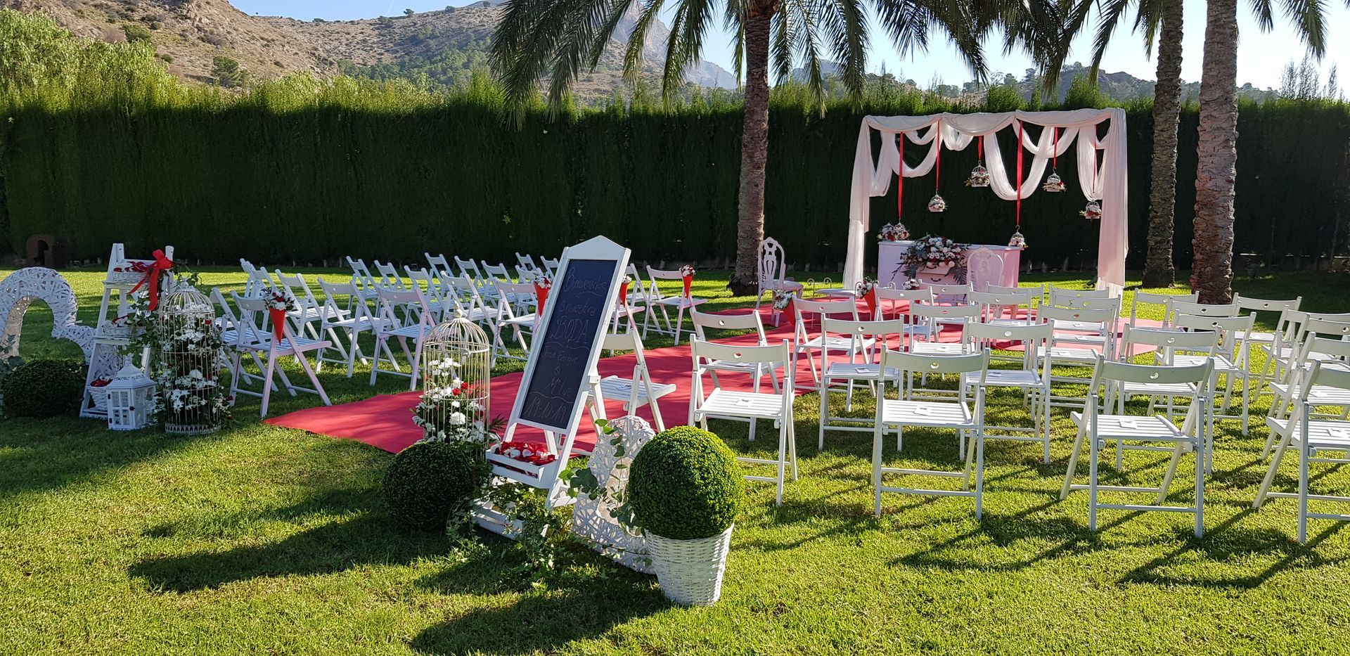 Una fila de sillas están alineadas en un campo de hierba para una ceremonia de boda.