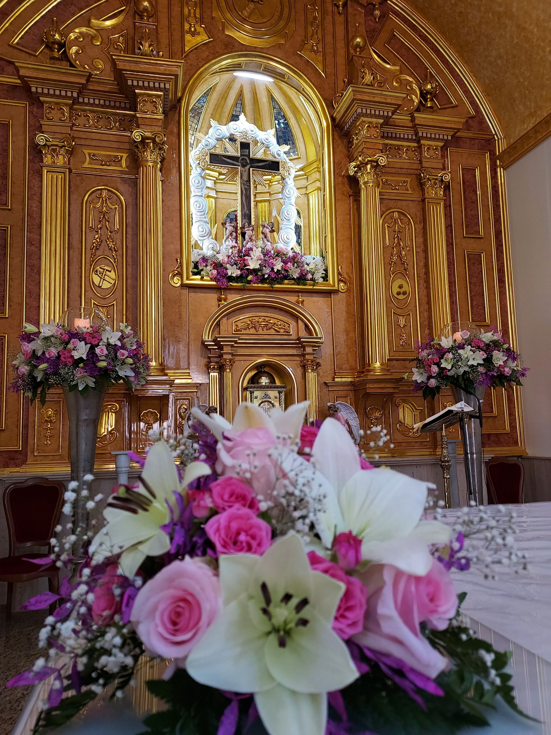Un altar de iglesia decorado con flores rosas y blancas.