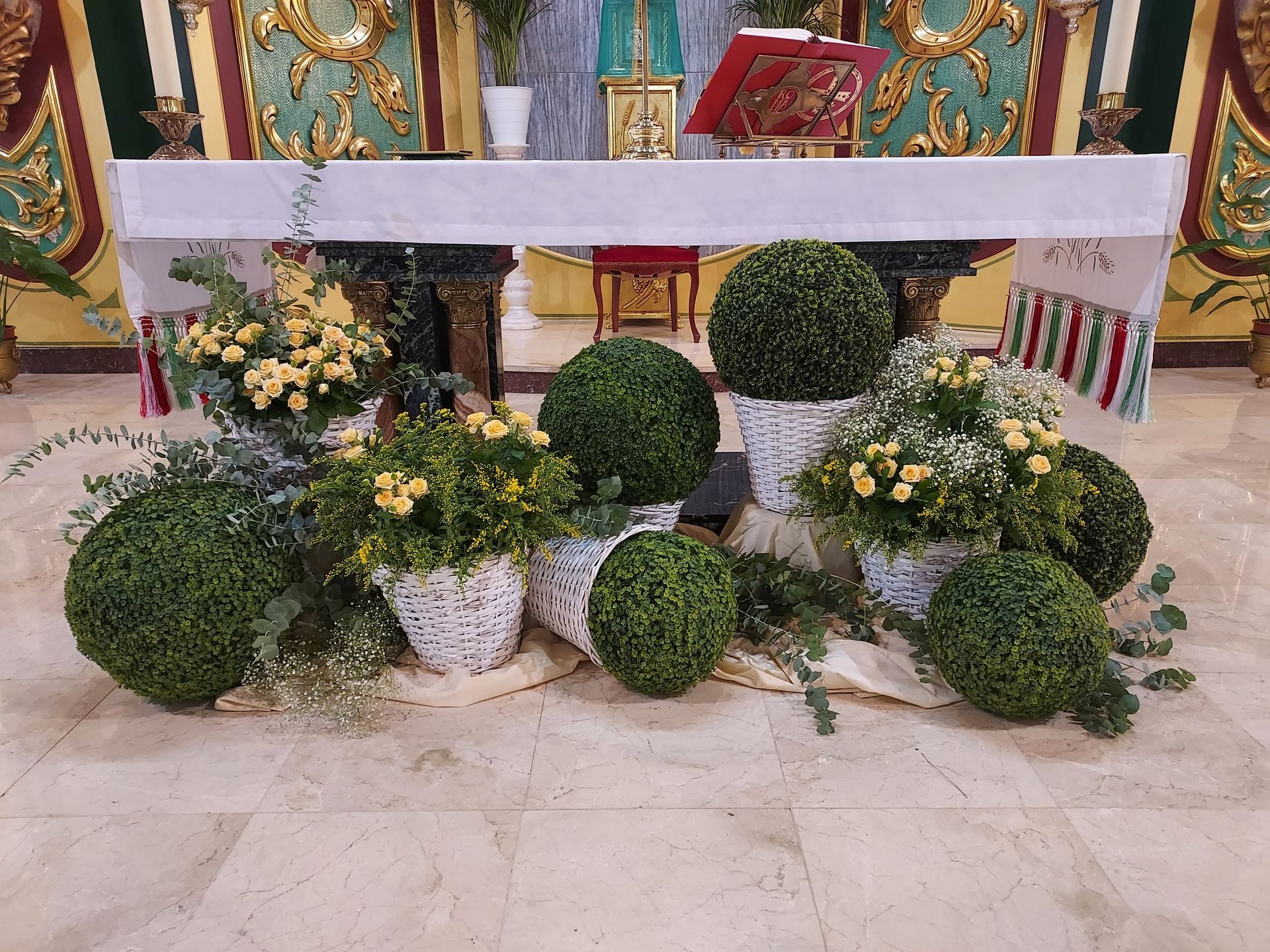Un altar de iglesia decorado con plantas en macetas y flores.