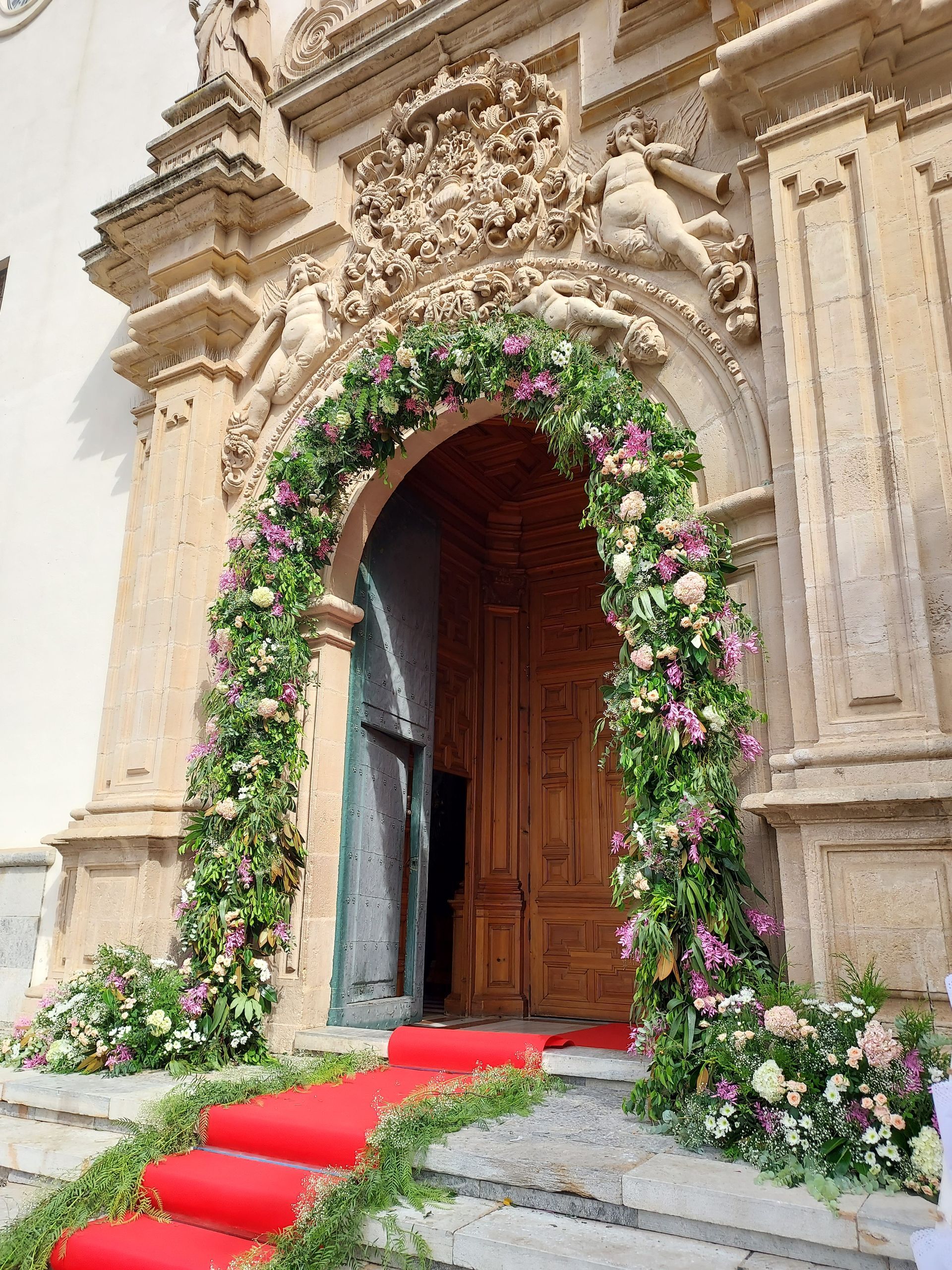 Un edificio con una puerta decorada con flores y vegetación.