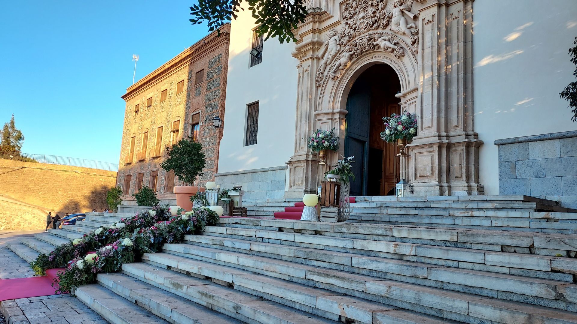 Los escalones de una iglesia están decorados con flores y una alfombra roja.