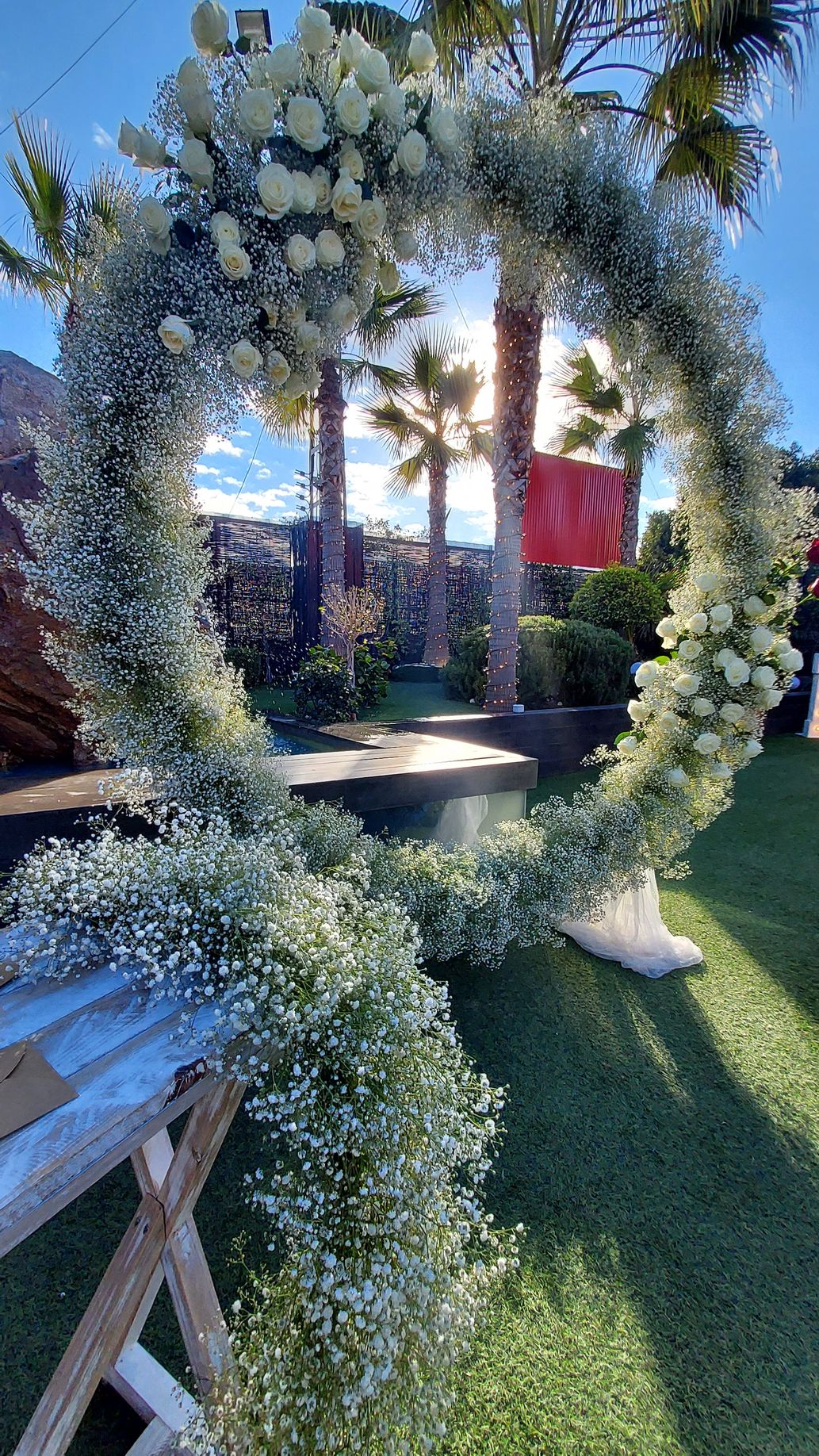 Una corona de flores blancas y flores de aliento del bebé está sobre una mesa.