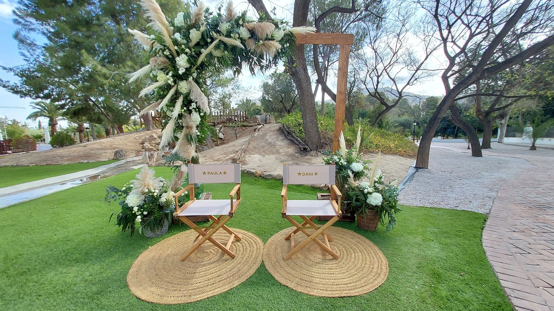 Dos sillas de director están colocadas bajo un arco de madera decorado con flores.