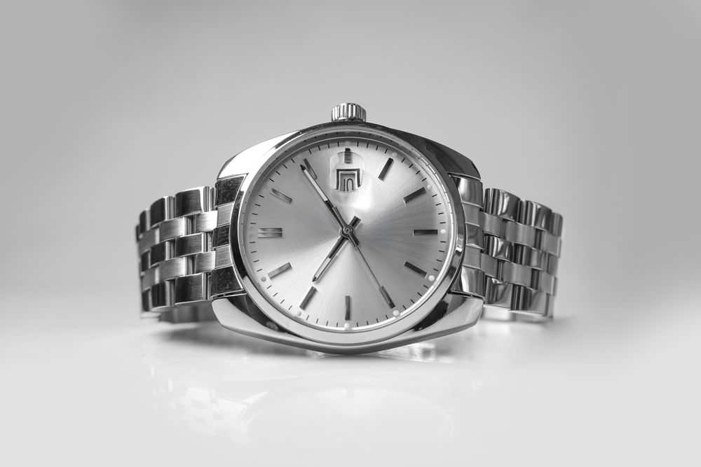 Reloj de pulsera plateado con correa metálica sobre fondo gris claro