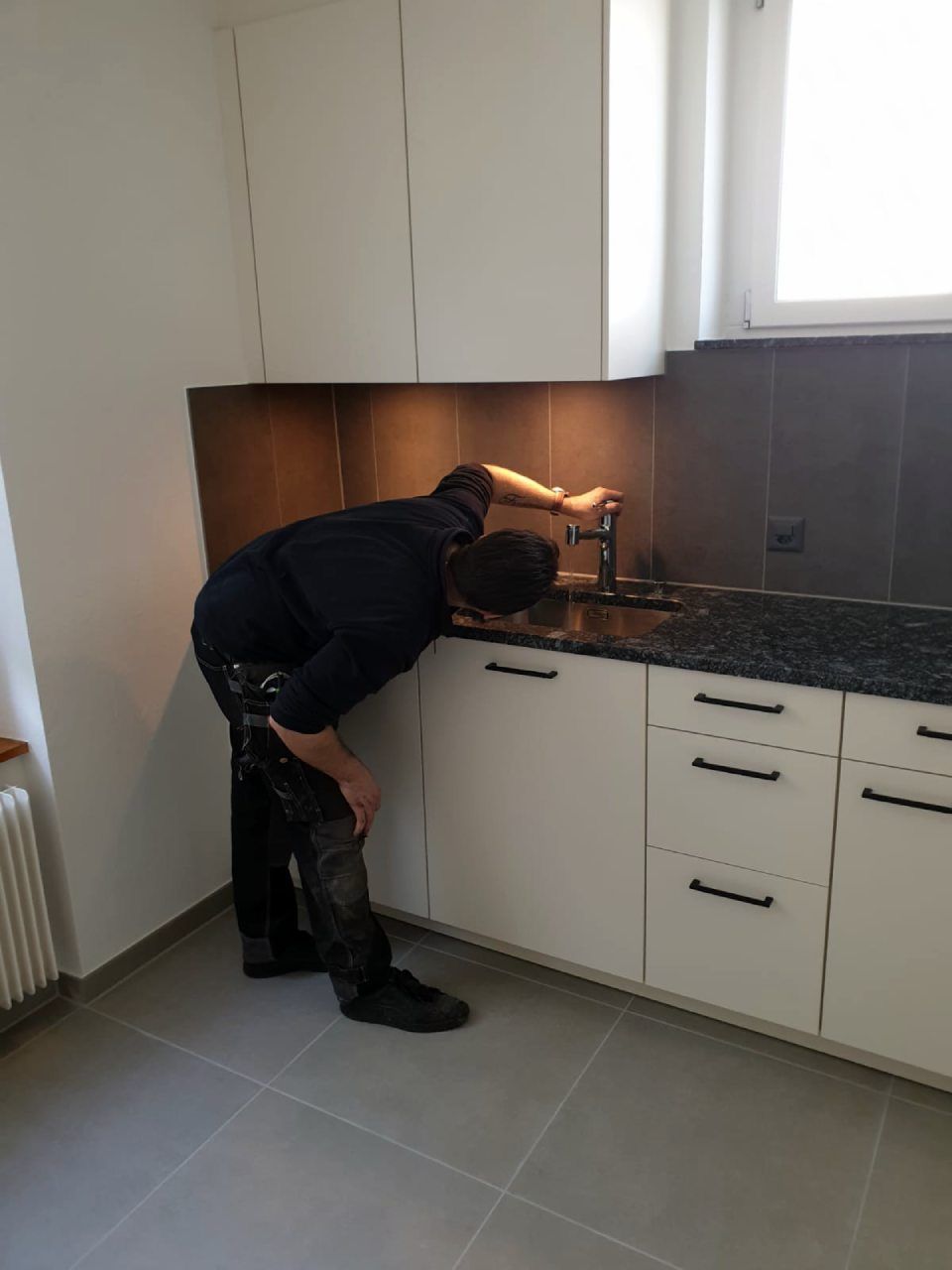 Ein Mann arbeitet an einer Spüle in einer Küche. Foto von der MS Sanitär Heizung GmbH