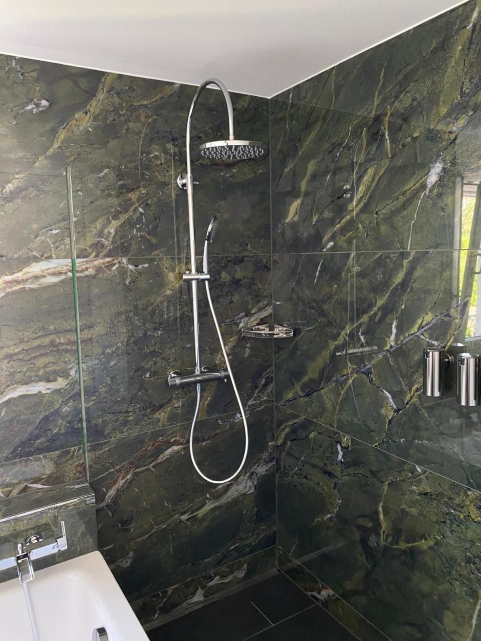 Ein Badezimmer mit grünen Fliesen und einem Duschkopf. Foto von der MS Sanitär Heizung GmbH