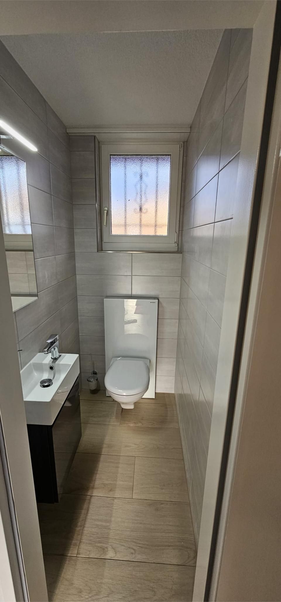 Ein Badezimmer mit Toilette, Waschbecken und Fenster. Foto von der MS Sanitär Heizung GmbH