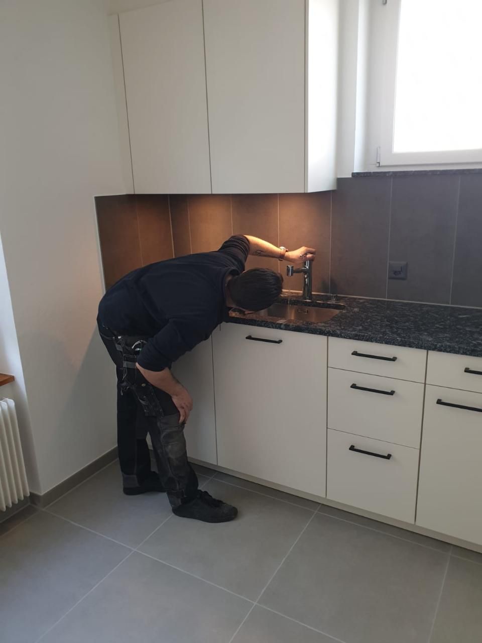 Ein Mann arbeitet an einer Spüle in einer Küche. Foto von der MS Sanitär Heizung GmbH