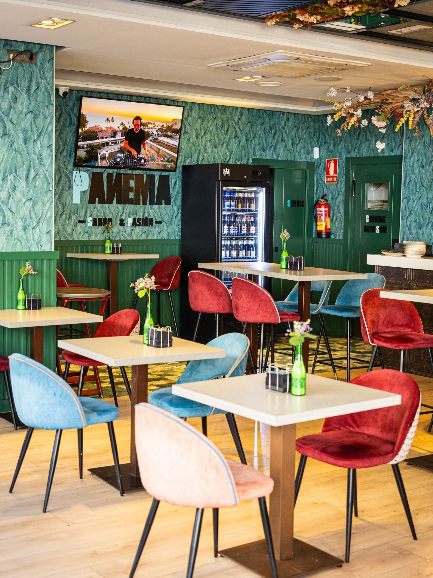 El interior del restaurante, muy bien iluminado, cuenta con mesas cuadradas y sillas de terciopelo en tonos rojos.