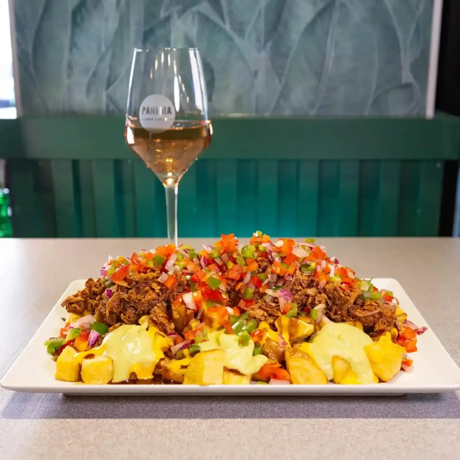 Un cóctel de color marrón rojizo en una copa con tallo y una rodaja de naranja, junto a un vaso de agua.