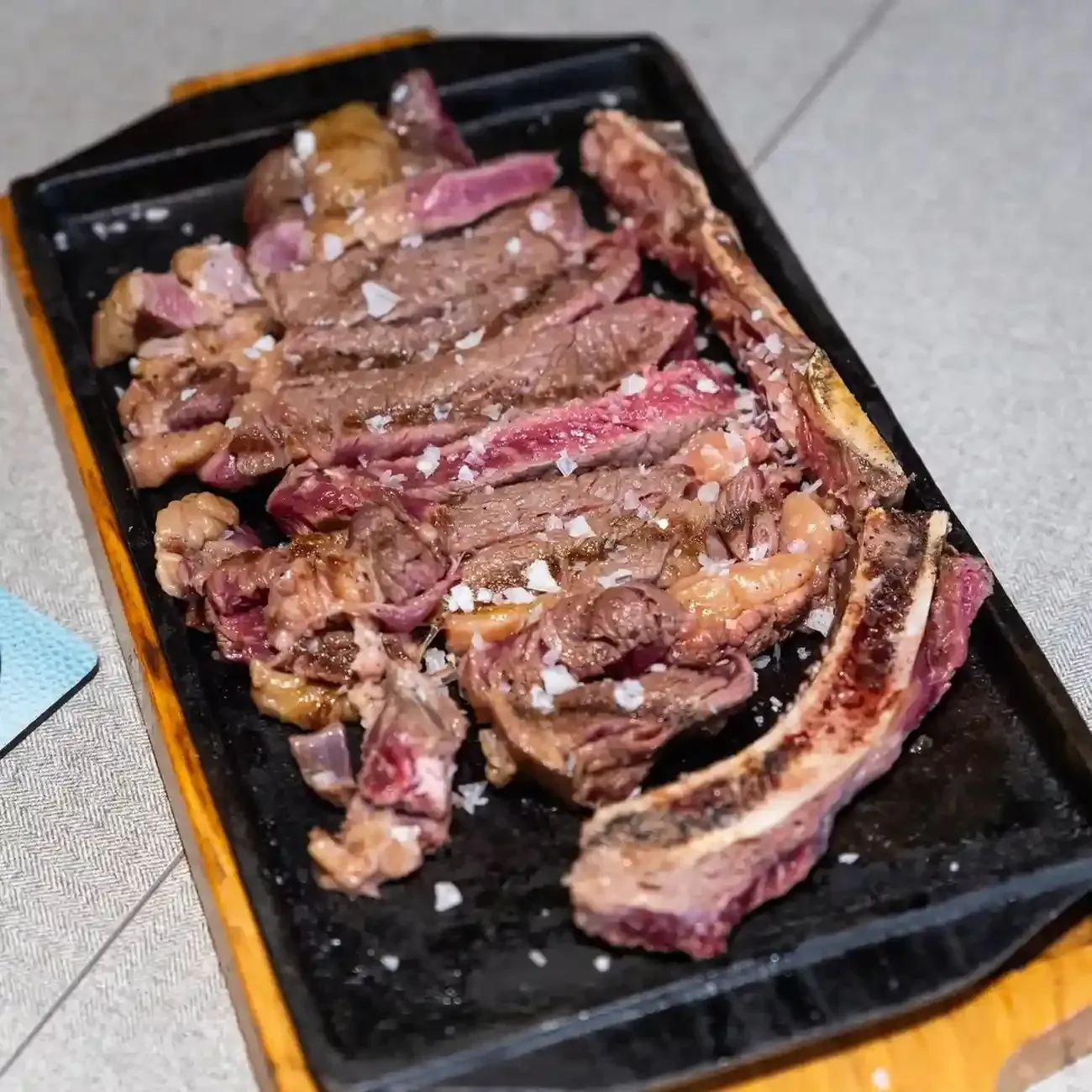 Un filete a la parrilla servido en un plato blanco con tomates salteados, pimientos, jalapeños en rodajas.