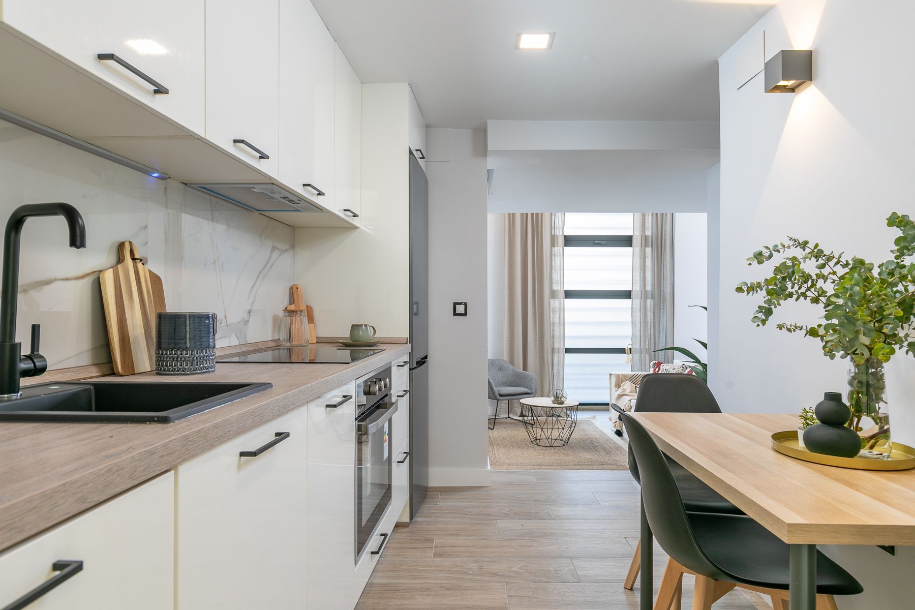 Una cocina con gabinetes blancos y una mesa y sillas de madera.