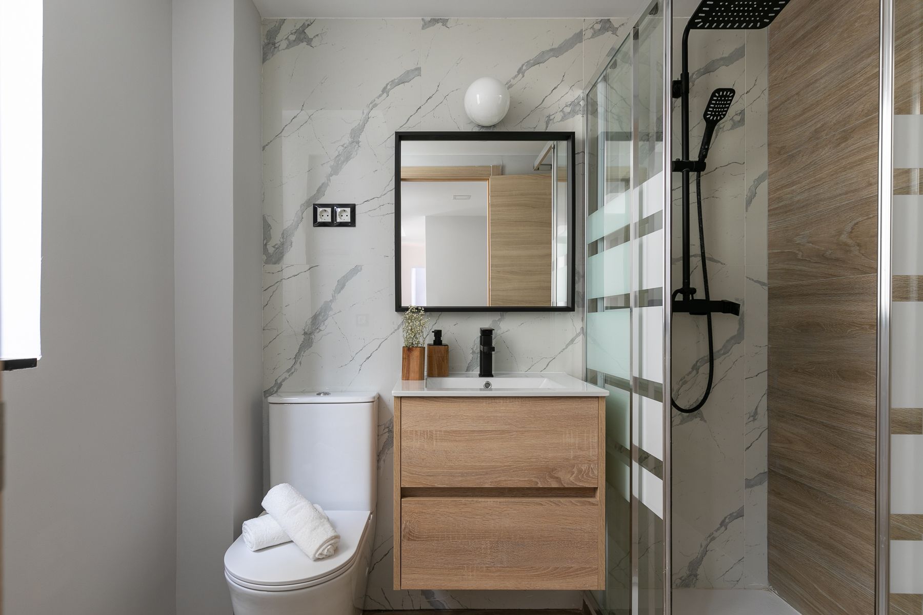 Un baño con inodoro, lavabo, espejo y ducha.
