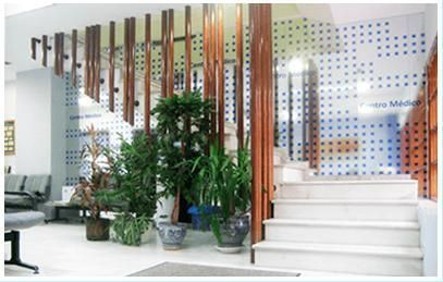 Vestíbulo de oficina moderno con plantas de interior, listones de madera, escalera blanca y una pared de vidrio con un patrón de puntos.