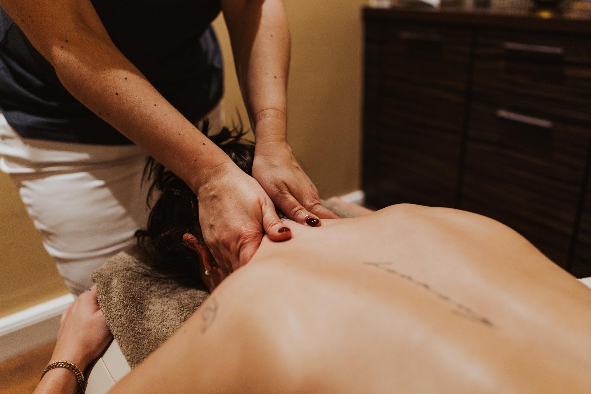 Ein Massagetherapeut knetet während einer Spa-Behandlung den Rücken eines Kunden.