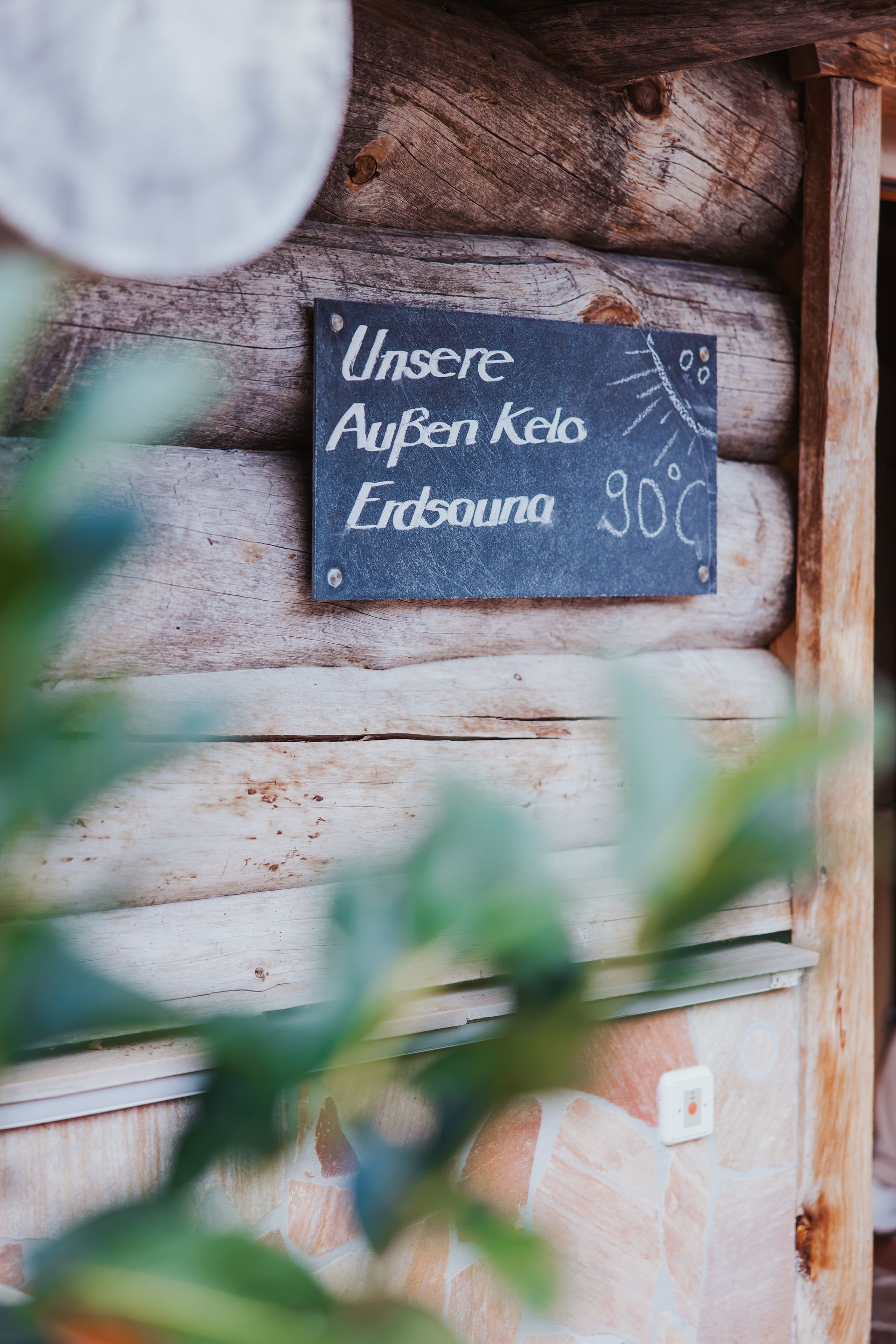 An einer Holzwand hängt ein Kreidetafelschild.