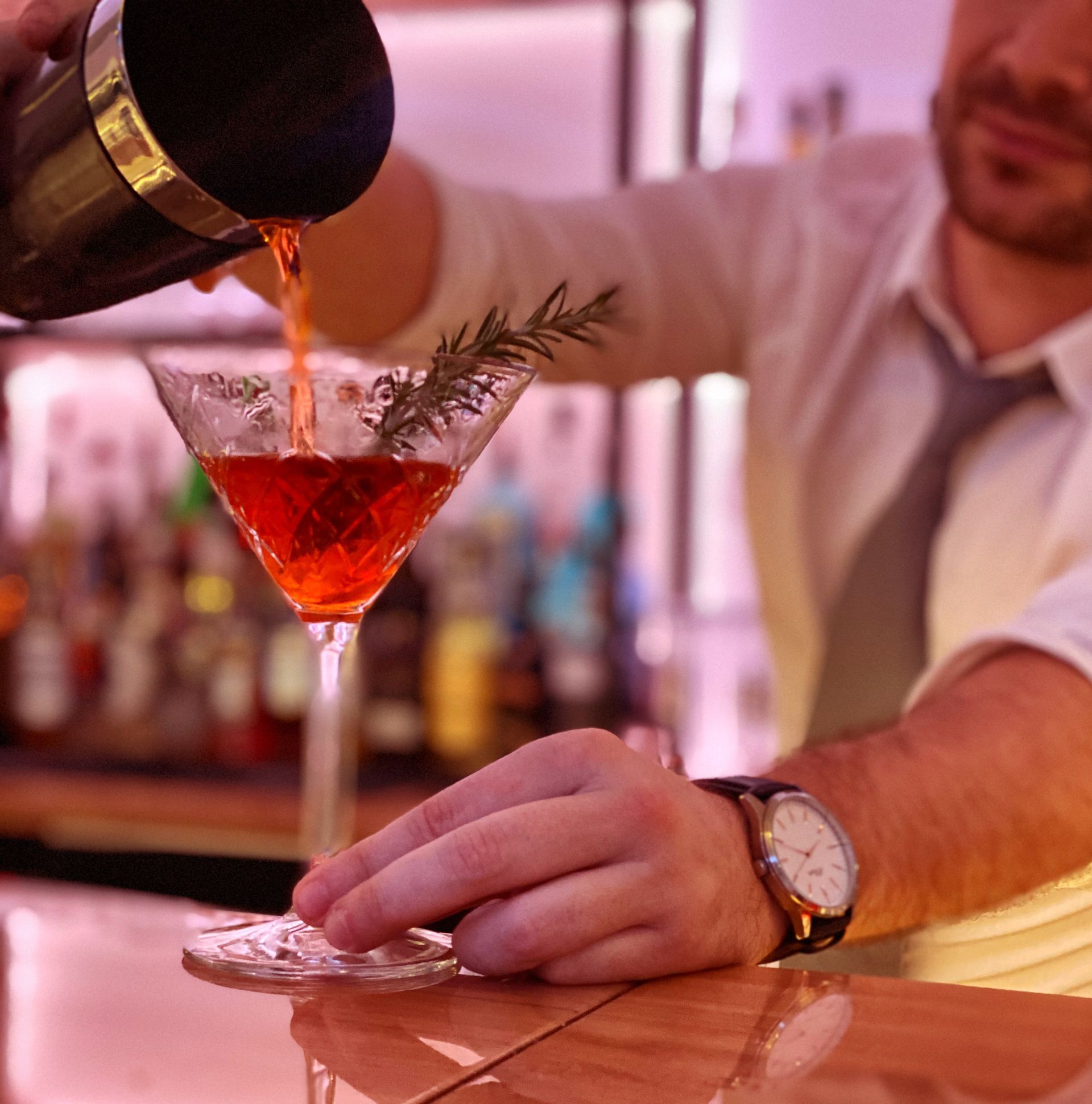 Ein Mann gießt einen Drink in ein Martiniglas