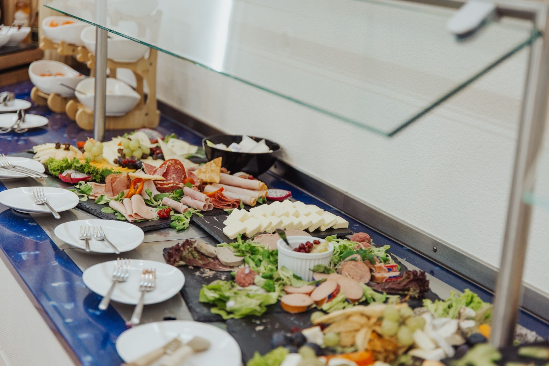Selbstbedienungsbuffet mit Salaten, Sandwiches, Gebäck und Tellern an einer langen Theke