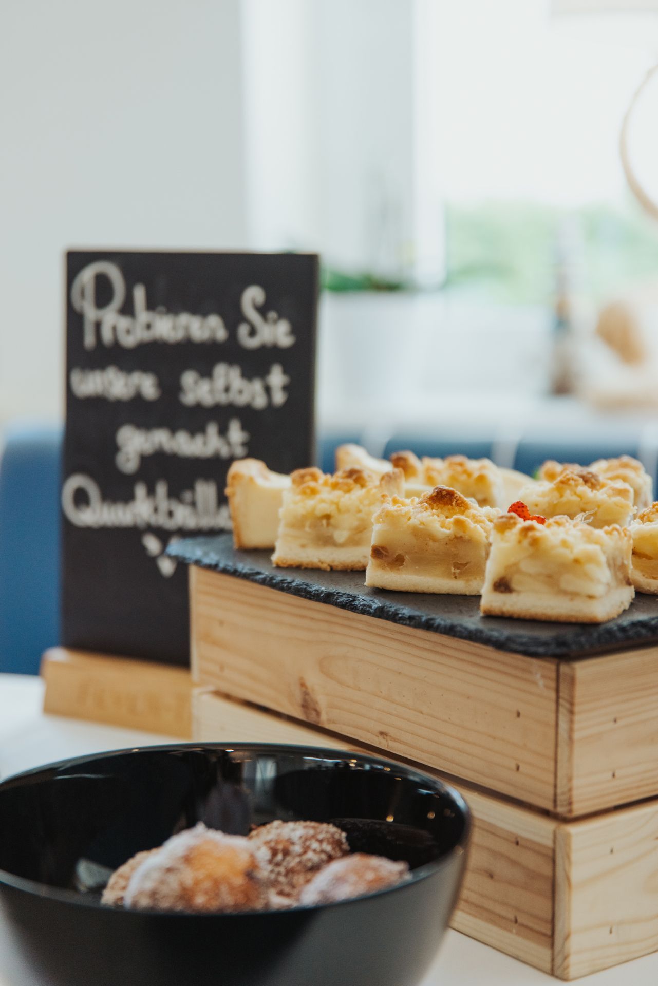 Ein Tablett mit Gebäckstücken auf einer Holzkiste neben einer schwarzen Schüssel und einem verschwommenen Menüschild.