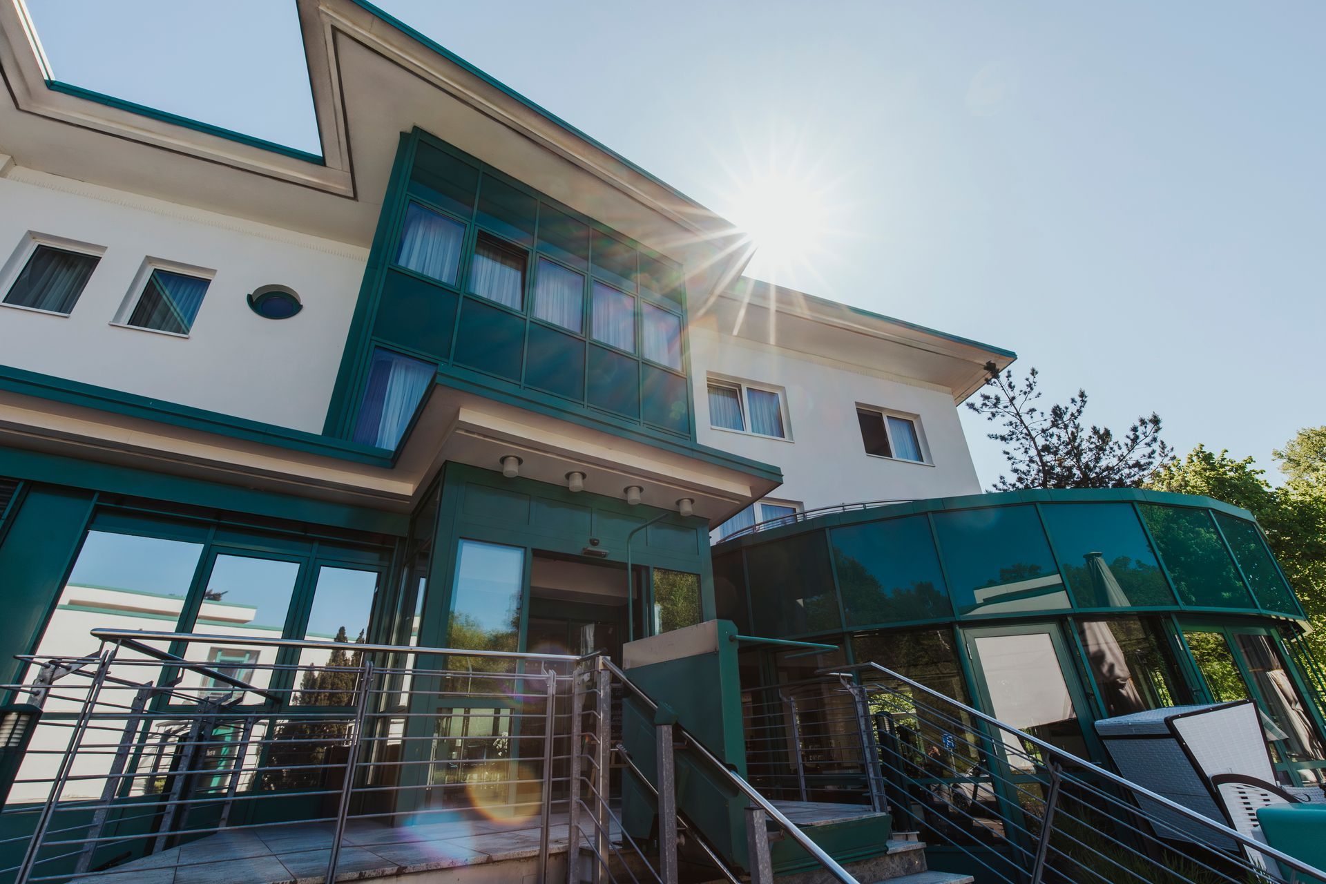 Modernes Gebäude mit türkisfarbener und weißer Fassade; helles Sonnenlicht.