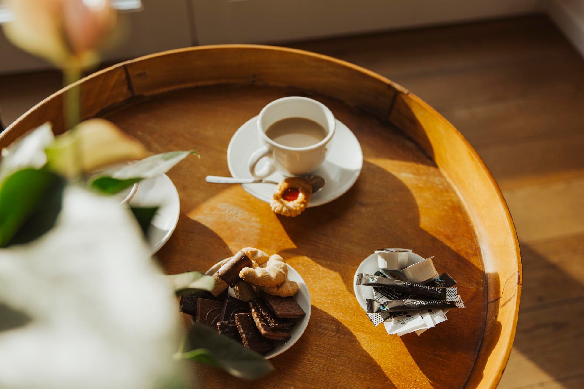 Ein Holztisch mit einer Tasse Kaffee, Keksen und einem Donut.
