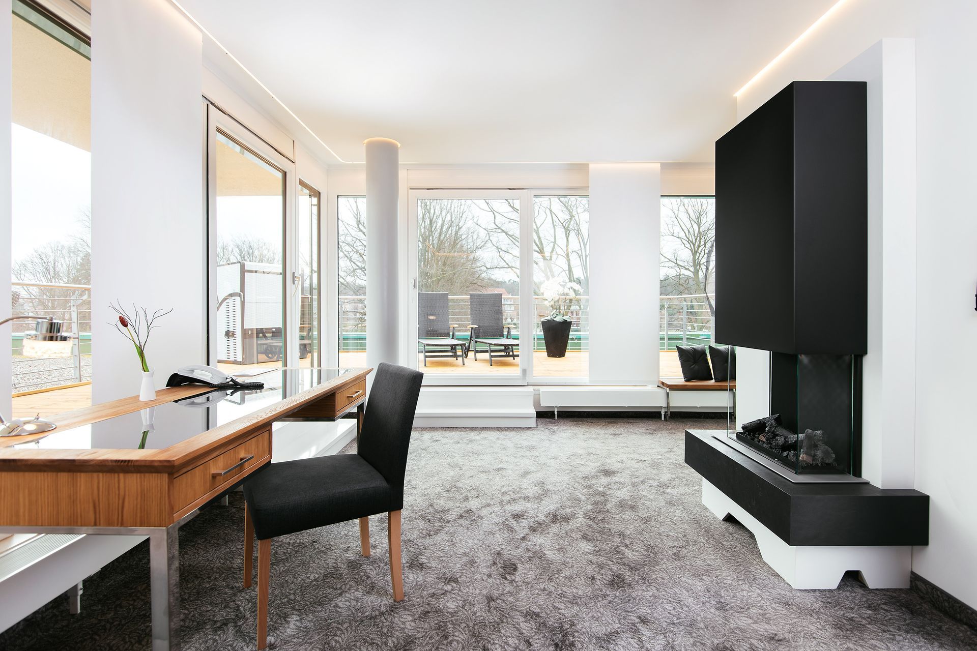 Ein Wohnzimmer mit Schreibtisch und Stühlen und einem Kamin