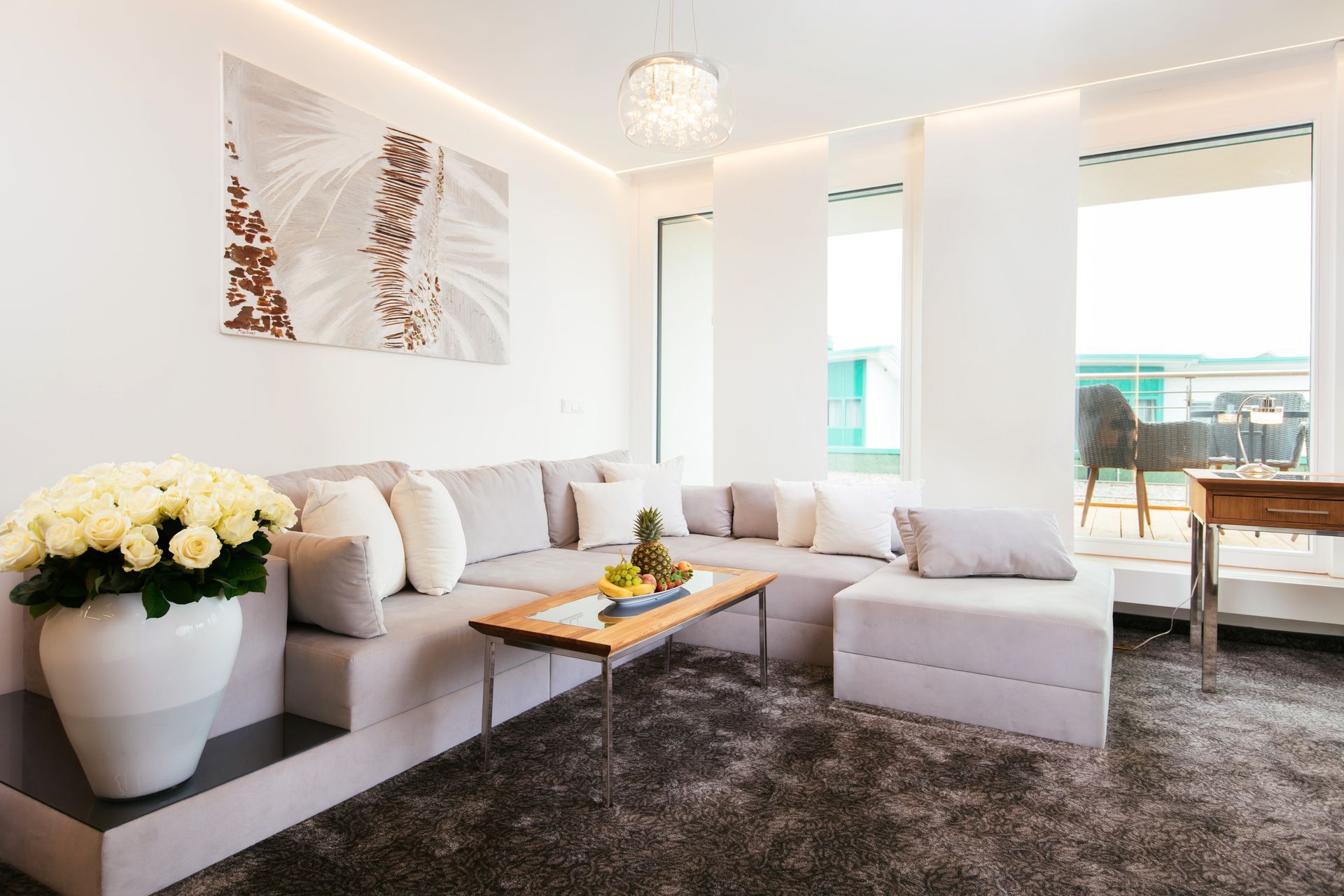 Wohnzimmer mit grauem Sofa, Couchtisch und weißen Rosen; neutrales Farbschema.