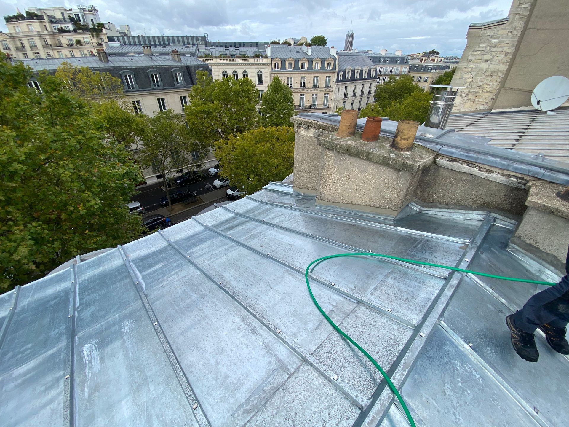 Une toiture en zinc et un tuyau vert.