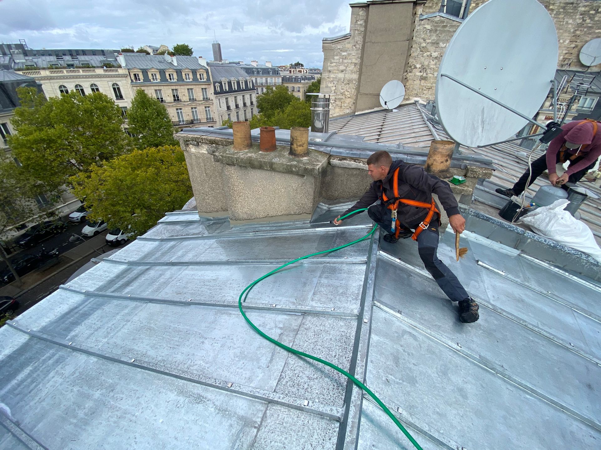Un couvreur nettoie une toiture en zinc.