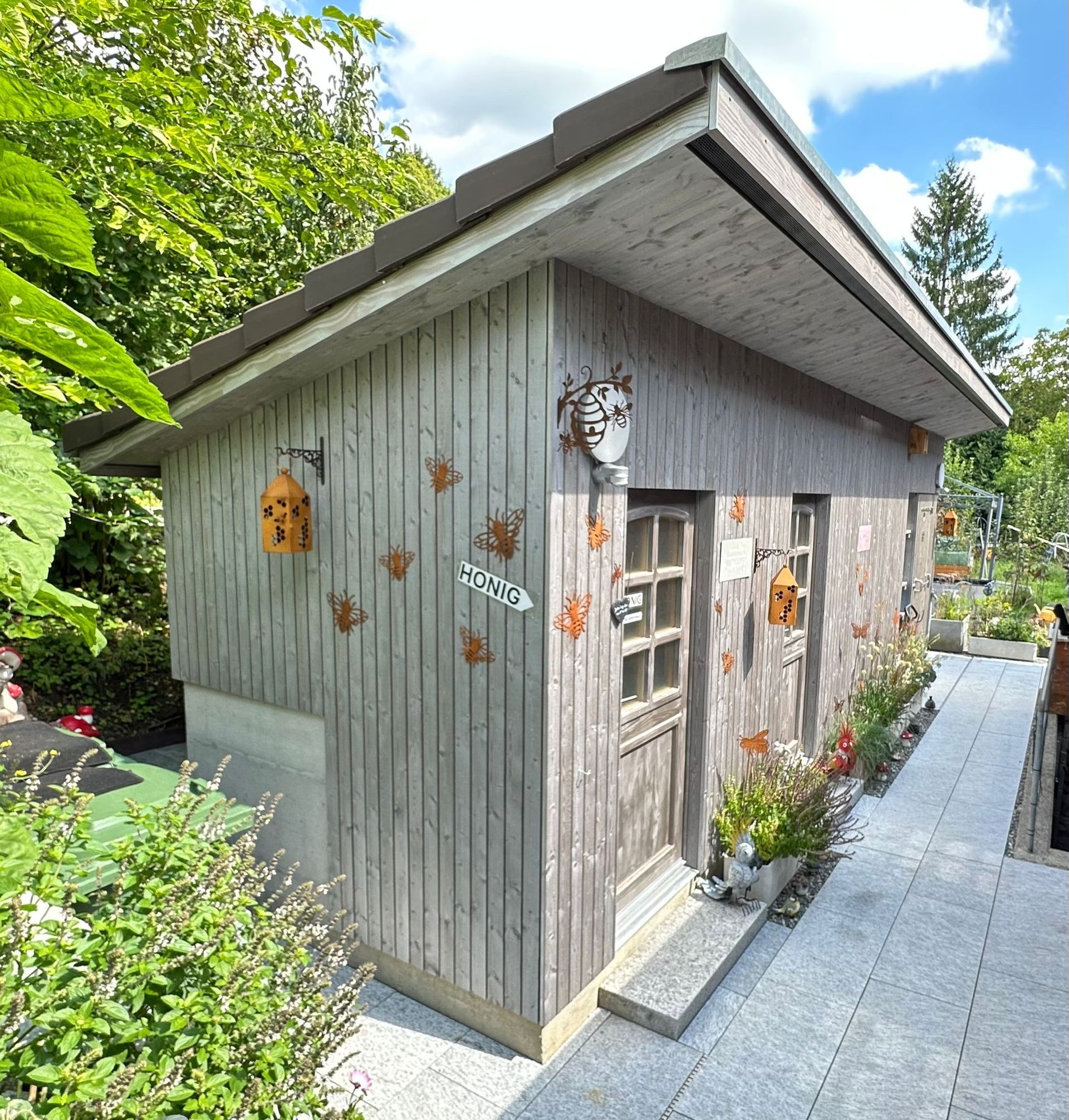 Holzschuppen mit dekorativen Akzenten und Pflanzgefäßen, im Freien an einem sonnigen Tag.