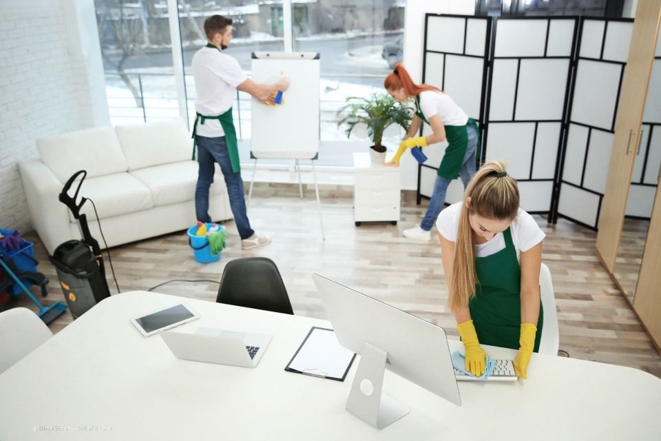 Multiline GmbH - Vier Reinigungsfachkräfte bei der Reinigung von verschiedenen Innenmöbeln und Elementen eines Bürozimmers