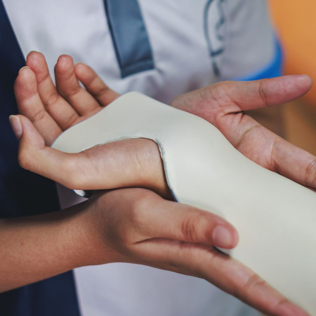 Une orthoprothésiste qui moule une attelle sur le poignet d'un patient.