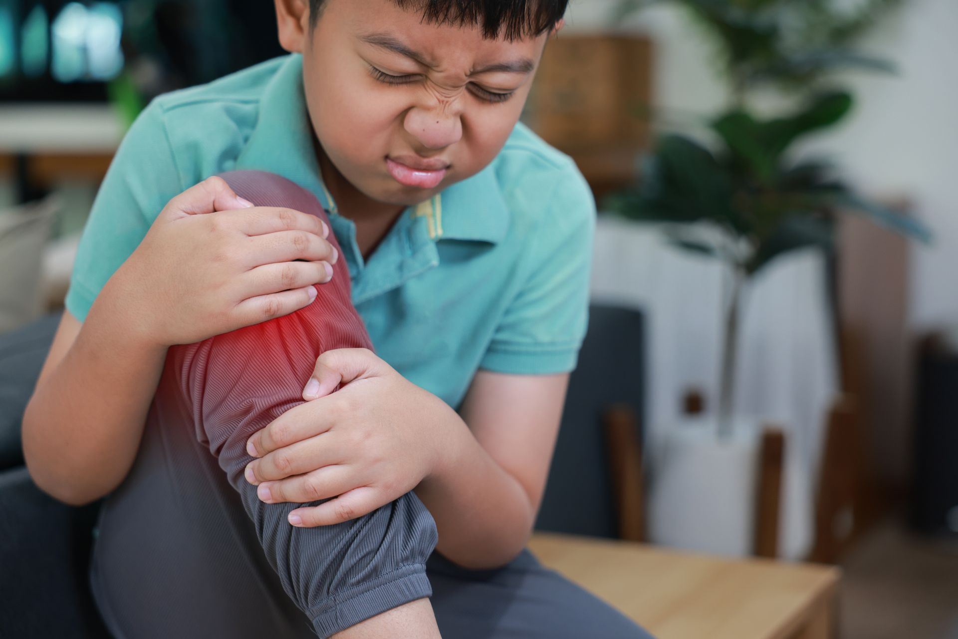 Un enfant qui se tient la jambe et grimace de douleur.