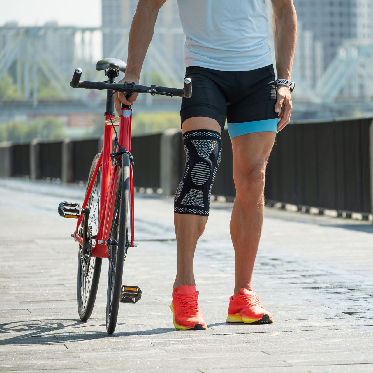 Un sportif portant une genouillère, à côté de son vélo.
