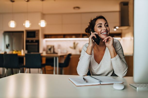 Une femme souriante au téléphone.