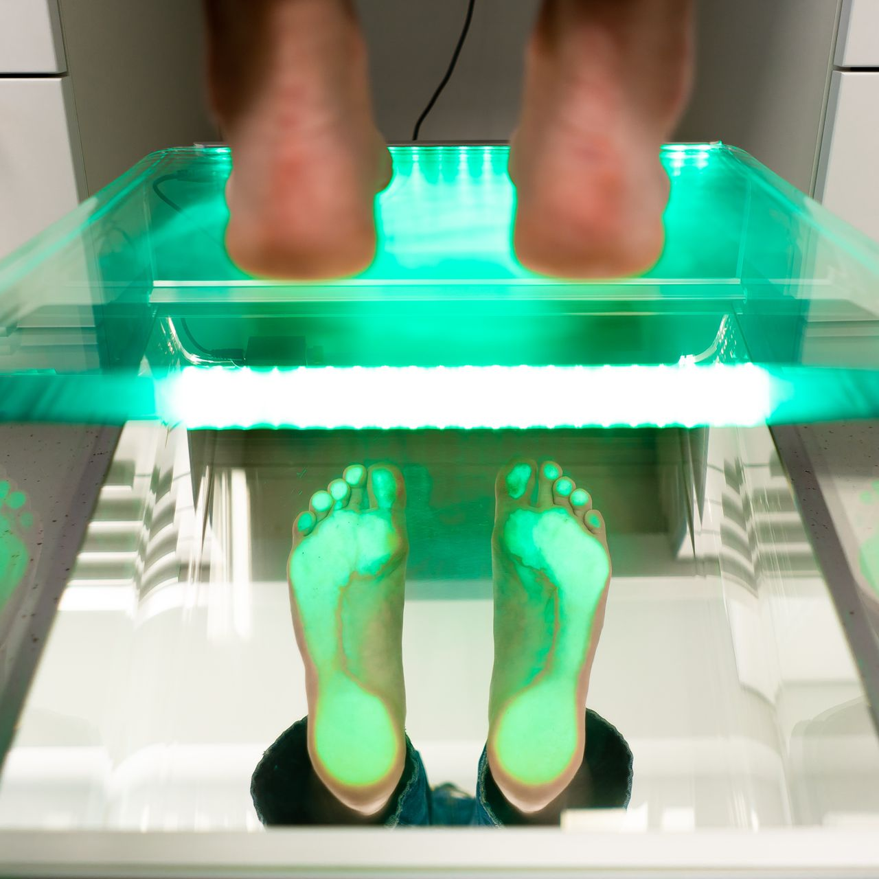Gros plan sur les pieds d'une personne posés sur un podoscope.