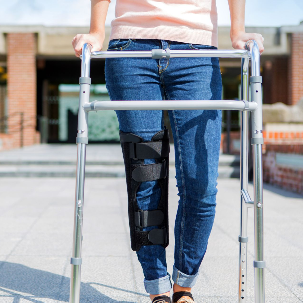 Une personne portant une genouillère marche avec un déambulateur.