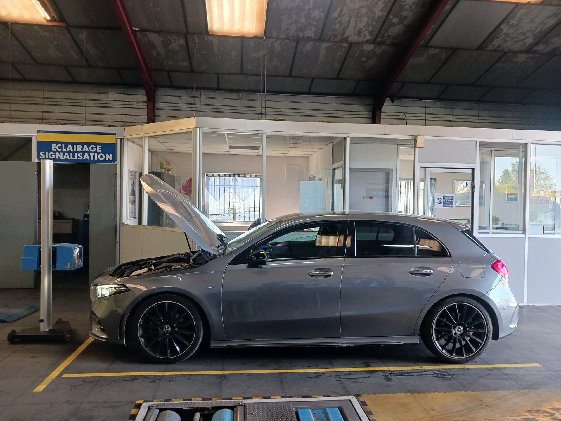 Berline grise à hayon, capot ouvert, dans un garage.