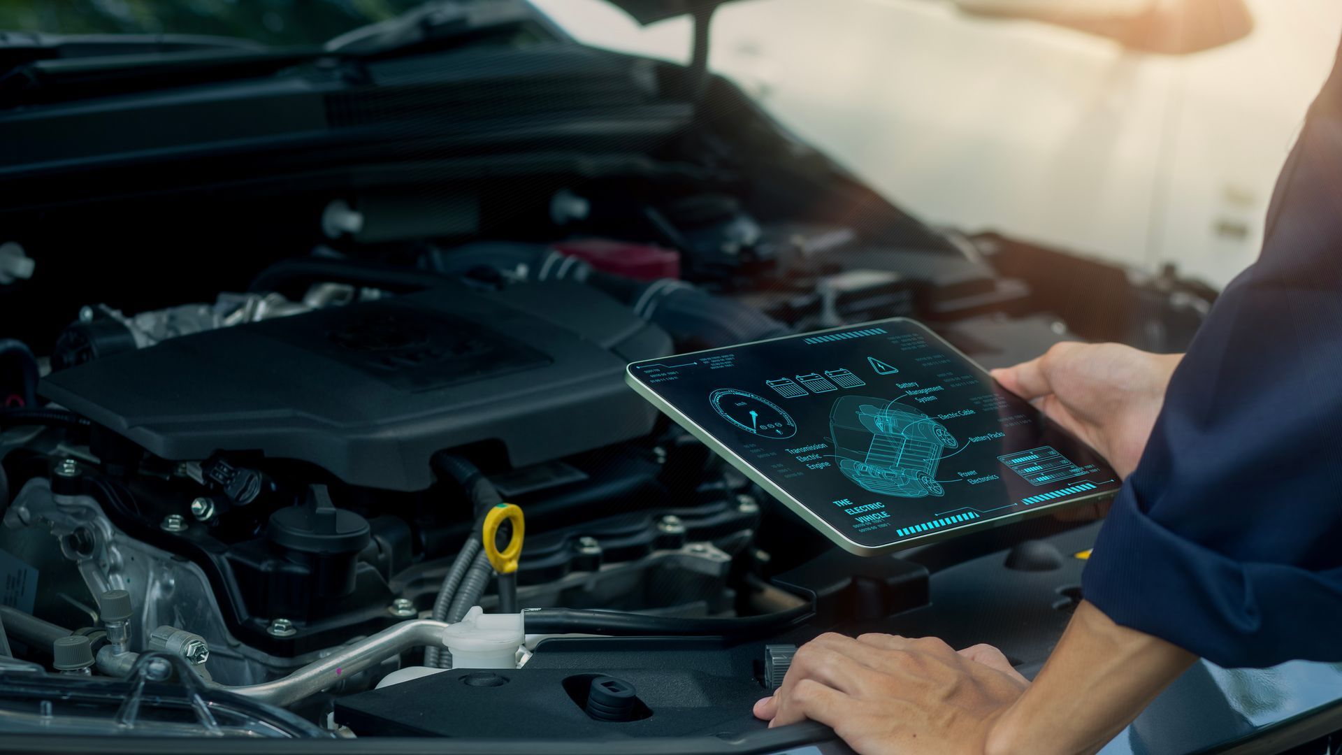 Un mécanicien utilise une tablette pour diagnostiquer un moteur de voiture dans un garage.