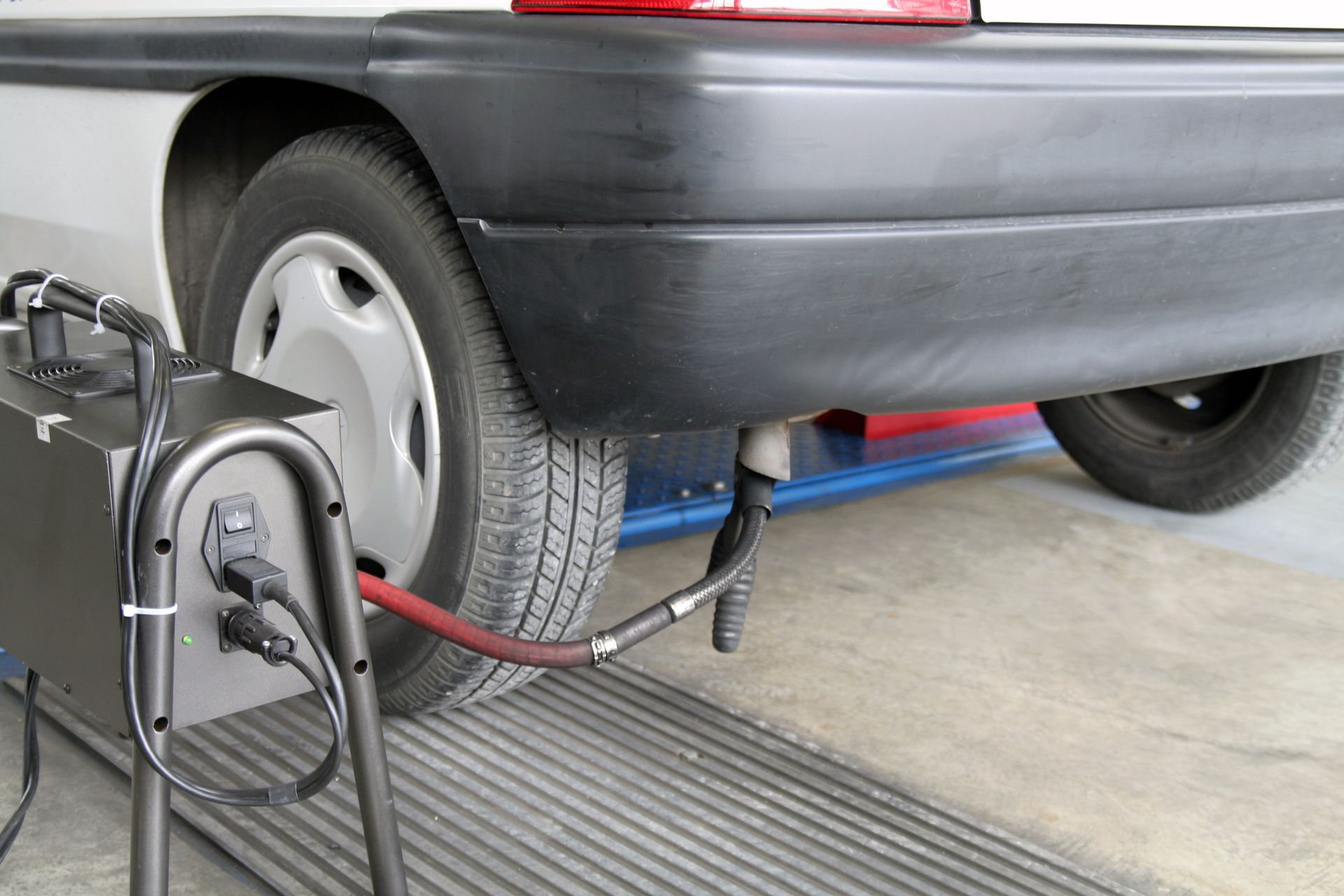 Voiture branchée à un banc d'essai de châssis dans un garage, avec un câble relié à la roue arrière.